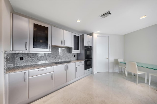 kitchen featuring black appliances, decorative backsplash, light stone counters, and light tile patterned floors