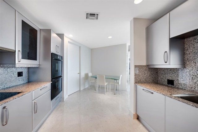 kitchen featuring light stone countertops, white cabinetry, and backsplash