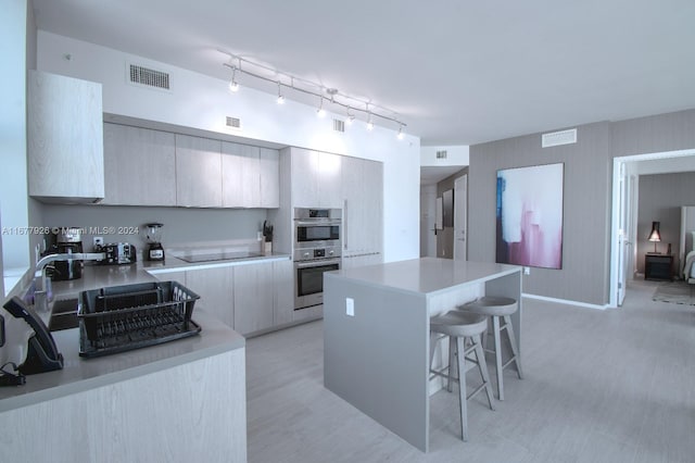 kitchen featuring a kitchen island, double oven, a kitchen bar, and black electric cooktop