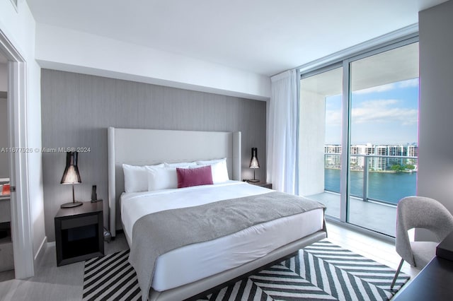 bedroom featuring a water view, access to outside, and floor to ceiling windows