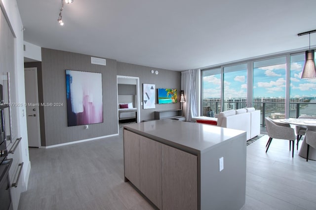 kitchen featuring a wall of windows, decorative light fixtures, and light hardwood / wood-style floors