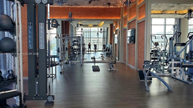 gym featuring brick wall and dark hardwood / wood-style flooring