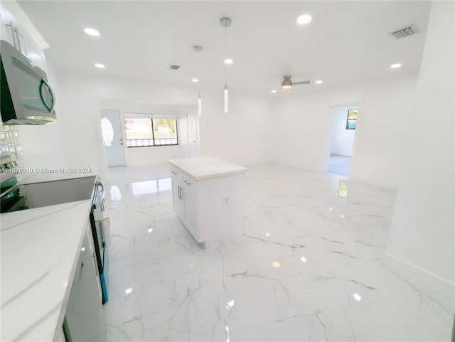 kitchen featuring white cabinets, stove, a center island, and pendant lighting