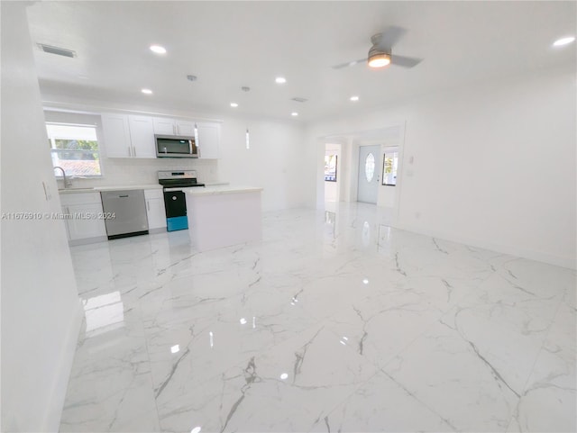 kitchen featuring appliances with stainless steel finishes, sink, white cabinetry, ceiling fan, and decorative backsplash