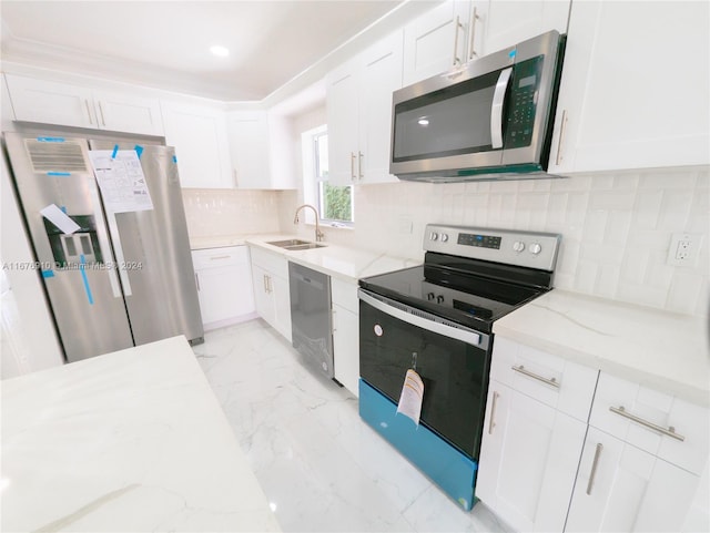 kitchen with light stone countertops, appliances with stainless steel finishes, sink, backsplash, and white cabinetry