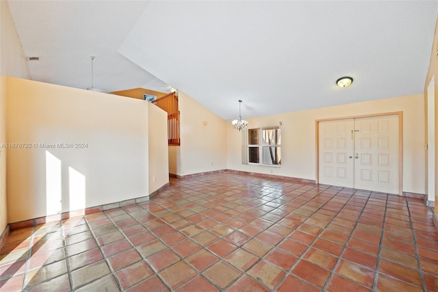 tiled empty room with lofted ceiling and a chandelier