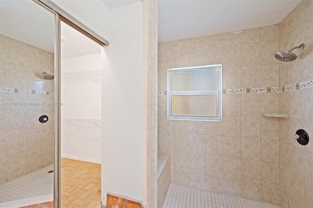 bathroom with parquet floors, a textured ceiling, and tiled shower