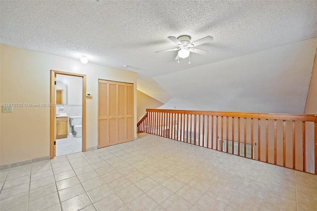 additional living space with vaulted ceiling, a textured ceiling, and ceiling fan