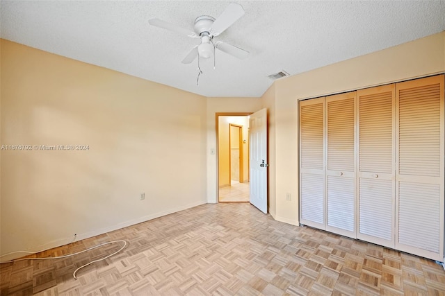 unfurnished bedroom featuring a closet, a textured ceiling, light parquet floors, and ceiling fan