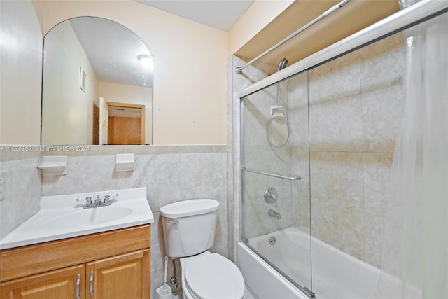 full bathroom featuring tile walls, vanity, enclosed tub / shower combo, and toilet