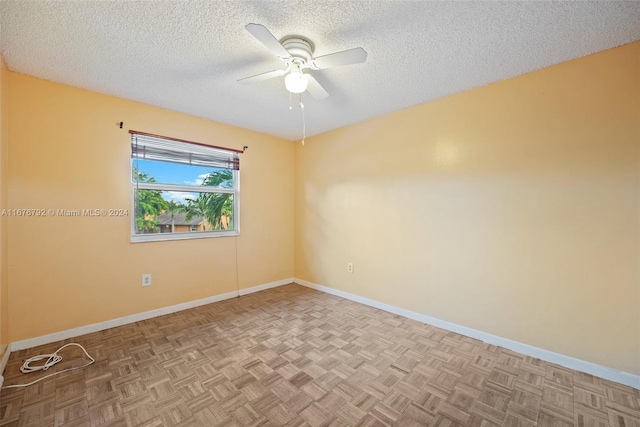 spare room with a textured ceiling, light parquet flooring, and ceiling fan