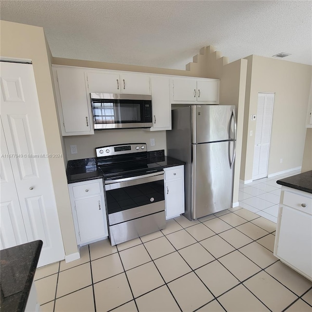 kitchen featuring stainless steel appliances, white cabinetry, light tile patterned floors, and a textured ceiling