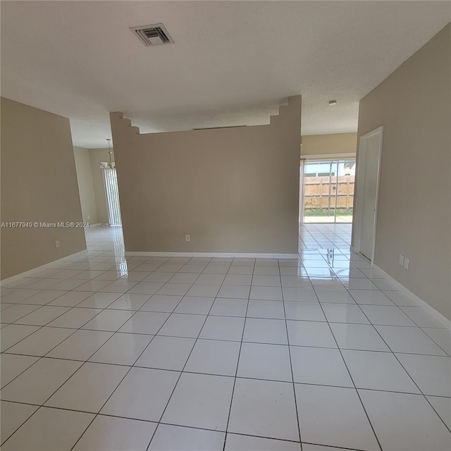 unfurnished room featuring a notable chandelier and light tile patterned floors