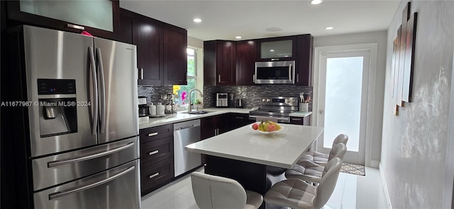 kitchen featuring sink, a kitchen island, stainless steel appliances, decorative backsplash, and a breakfast bar area