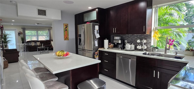 kitchen featuring tasteful backsplash, a kitchen island, a breakfast bar, sink, and stainless steel appliances