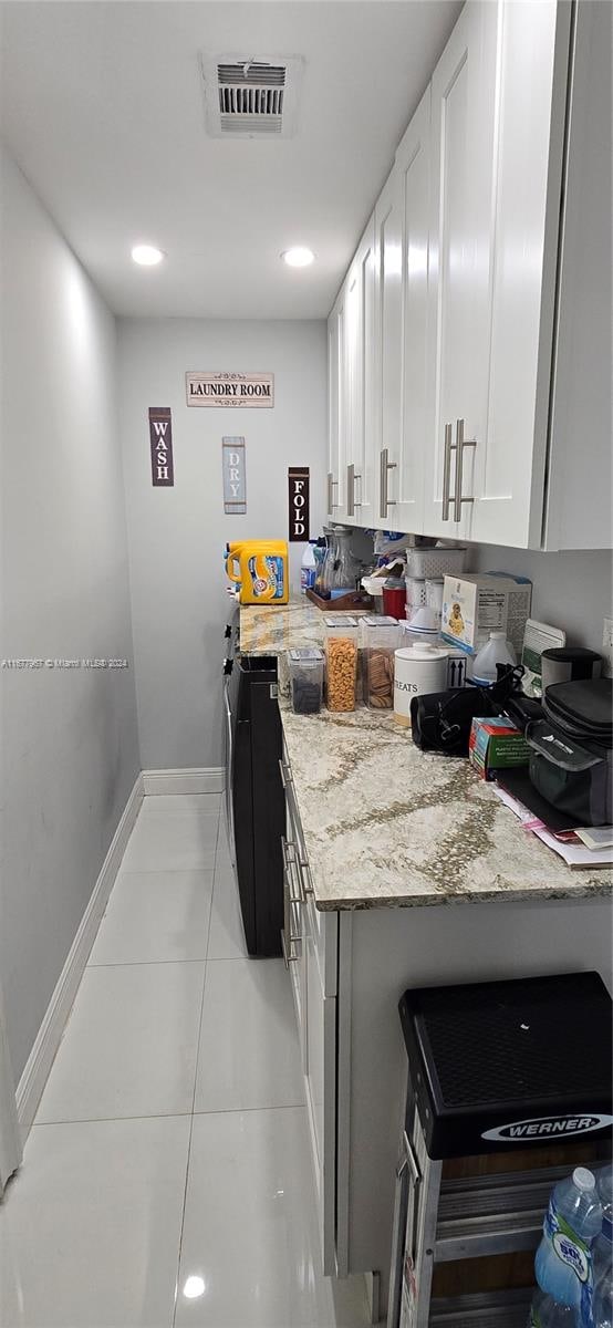 kitchen with light stone countertops, white cabinetry, and light tile patterned flooring