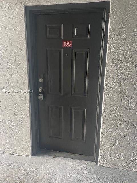 1068NBENOIST Farm Rd Unit 105, West Palm Beach, FL 33411 - doorway to property featuring stucco siding