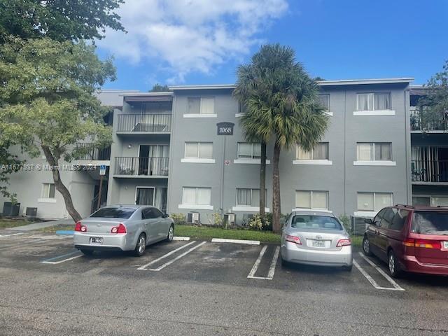 1068NBENOIST Farm Rd Unit 105, West Palm Beach, FL 33411 - view of apartment building / complex featuring uncovered parking