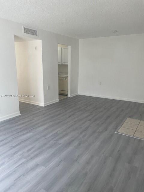 1068NBENOIST Farm Rd Unit 105, West Palm Beach, FL 33411 - spare room with baseboards, dark wood-style floors, and a textured ceiling