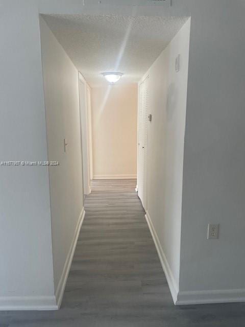 1068NBENOIST Farm Rd Unit 105, West Palm Beach, FL 33411 - hallway featuring baseboards, wood finished floors, and a textured ceiling