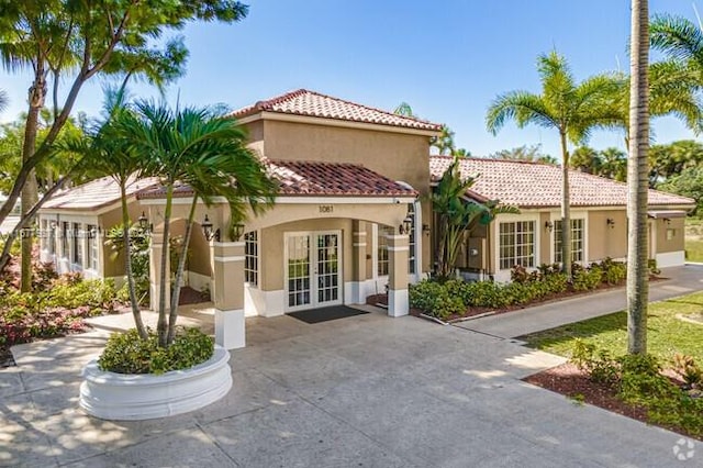 1068NBENOIST Farm Rd Unit 105, West Palm Beach, FL 33411 - view of front of house featuring french doors, stucco siding, and a tiled roof
