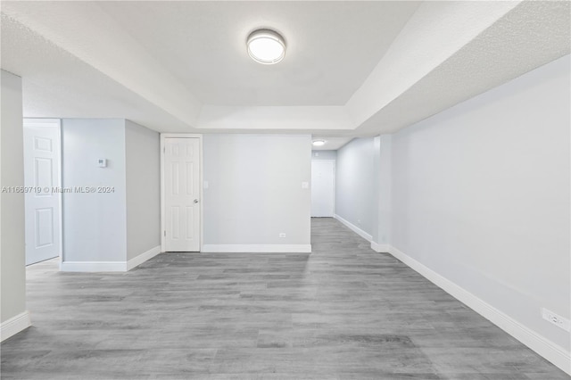 interior space with light wood-type flooring and a raised ceiling