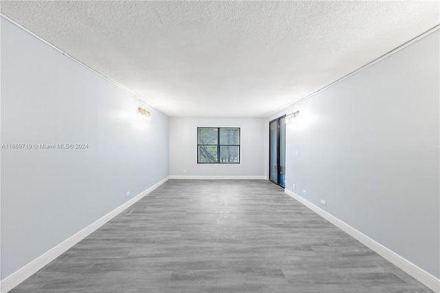 empty room with hardwood / wood-style floors and a textured ceiling