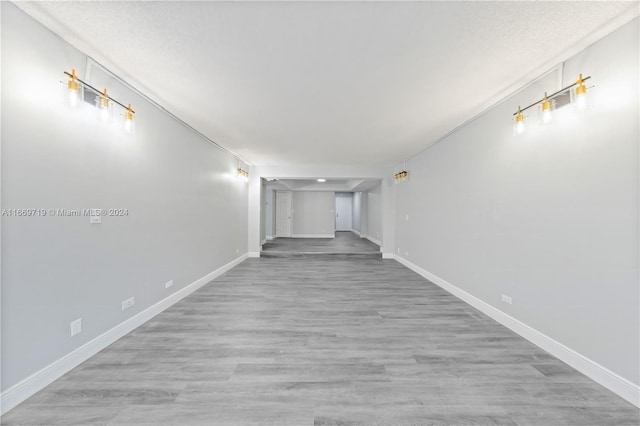 hall with a textured ceiling and light wood-type flooring