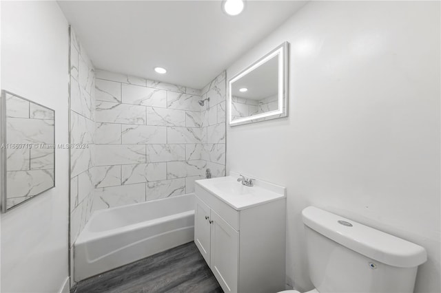 full bathroom featuring tiled shower / bath, vanity, hardwood / wood-style floors, and toilet