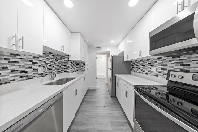 kitchen featuring appliances with stainless steel finishes, white cabinets, sink, and light wood-type flooring