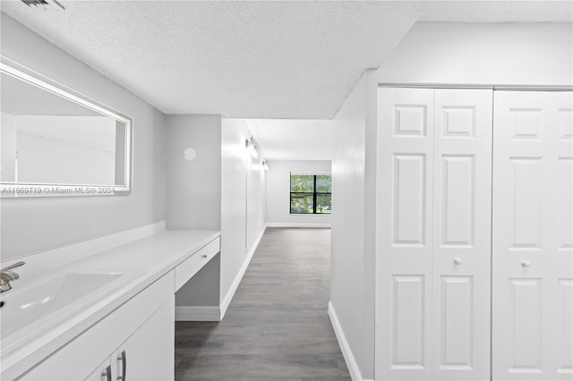 hall with a textured ceiling, sink, and dark hardwood / wood-style flooring