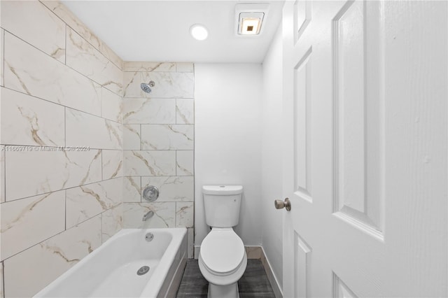 bathroom featuring tiled shower / bath combo, hardwood / wood-style flooring, and toilet