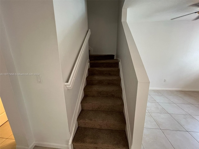 staircase featuring ceiling fan and tile patterned flooring