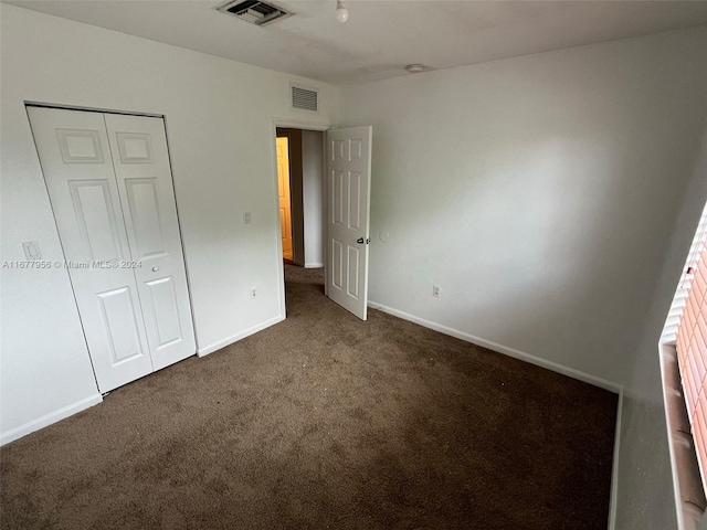 unfurnished bedroom featuring a closet and dark carpet