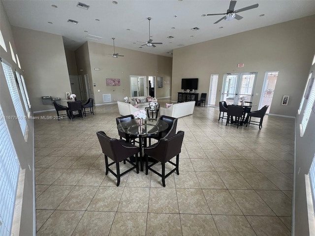 tiled dining space with ceiling fan and a towering ceiling