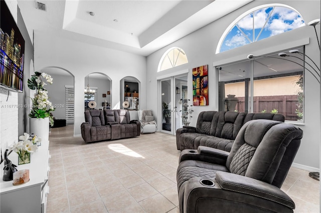 tiled living room with a chandelier, a towering ceiling, and a raised ceiling