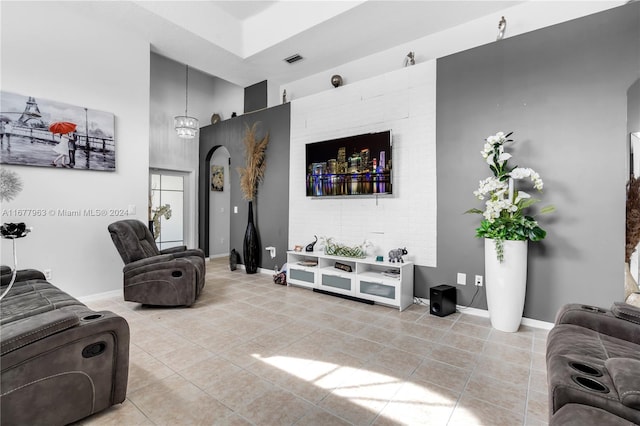 tiled living room featuring a towering ceiling and a chandelier