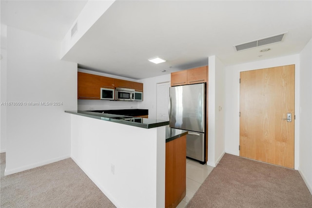 kitchen with kitchen peninsula, stainless steel appliances, and light carpet