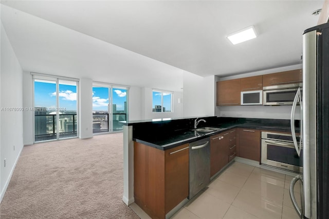 kitchen featuring kitchen peninsula, light colored carpet, sink, and appliances with stainless steel finishes