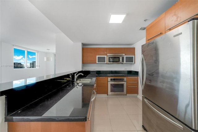 kitchen featuring stainless steel appliances, kitchen peninsula, sink, light tile patterned flooring, and pendant lighting