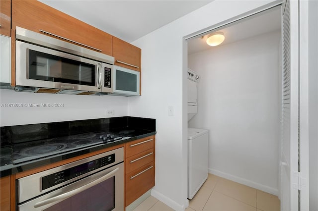 kitchen featuring stacked washer and dryer, appliances with stainless steel finishes, and light tile patterned floors