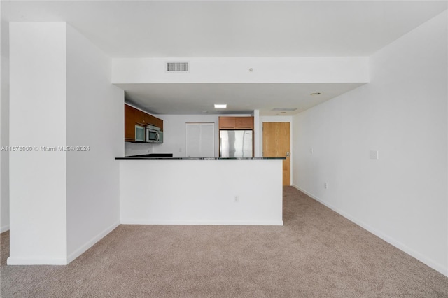 kitchen featuring stainless steel appliances, light colored carpet, and kitchen peninsula