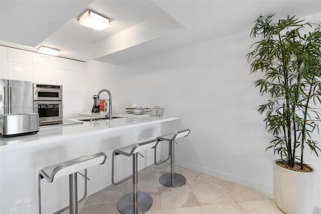 kitchen with white cabinetry, stainless steel appliances, sink, and light tile patterned flooring