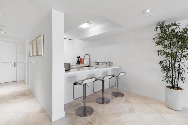 kitchen with sink, a breakfast bar, white cabinets, and kitchen peninsula