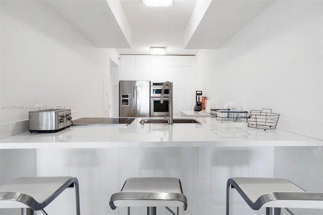 kitchen with a kitchen breakfast bar, kitchen peninsula, white cabinets, and stainless steel appliances