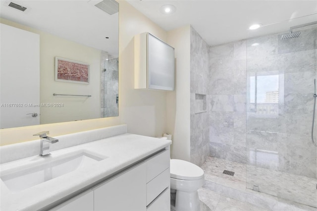 bathroom featuring vanity, a tile shower, and toilet