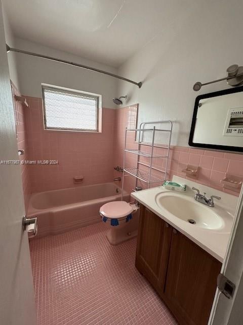 full bathroom featuring tile walls, toilet, vanity, tiled shower / bath combo, and tile patterned flooring