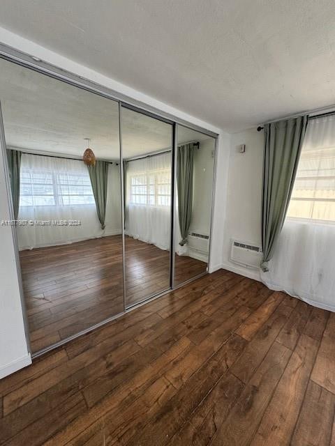 unfurnished bedroom featuring a closet, hardwood / wood-style flooring, and baseboard heating