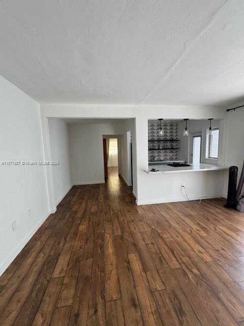 unfurnished living room featuring a textured ceiling and dark hardwood / wood-style floors