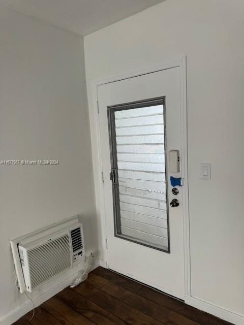 entryway featuring a wall unit AC and dark wood-type flooring